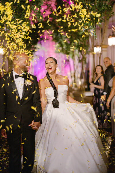 Happy bride and groom walking through confetti