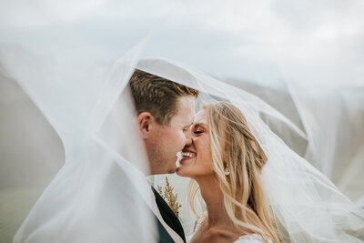 couple kissing under veil at wedding day