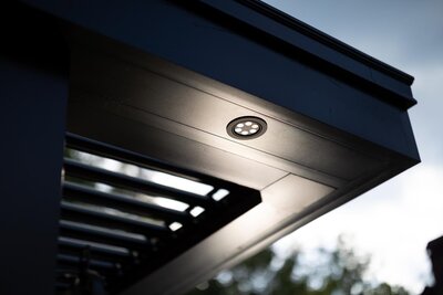 LED lights integrated into the underside of a black StruXure pergola frame. 