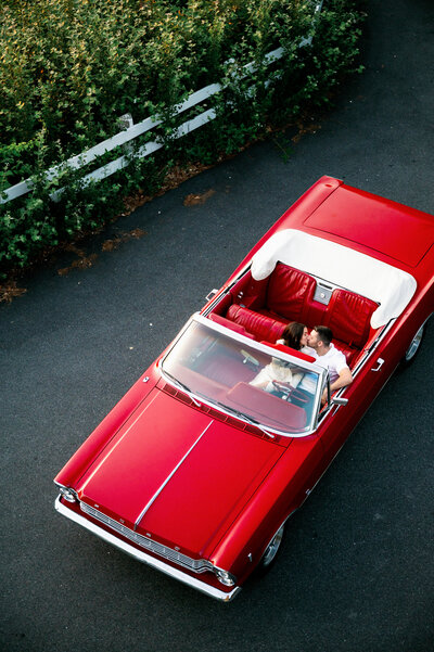 couple kissing in red convertible