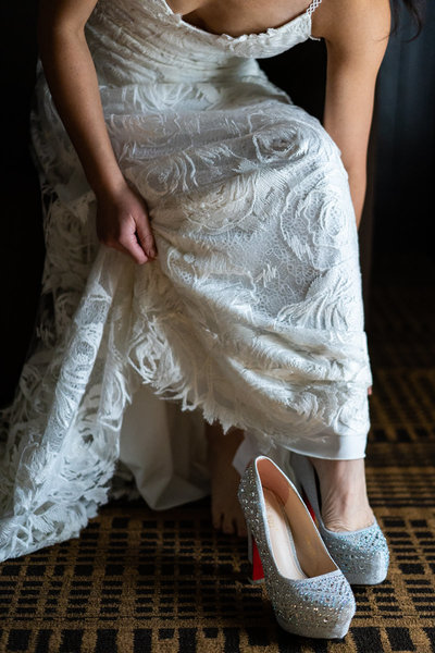 Bride putting her shoes on in front of window light