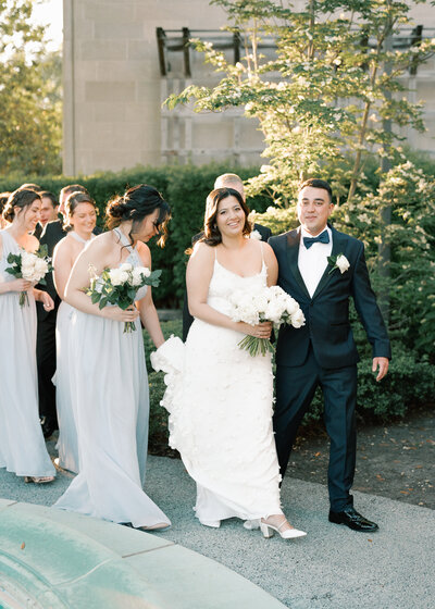 Bride and groom walk along  path smiling.