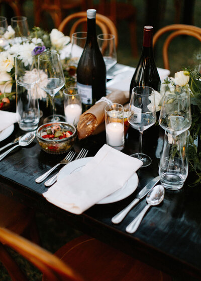 Al Fresco Dinner Table set with glassware, plates, wine, and bread at The Paramour Estate.