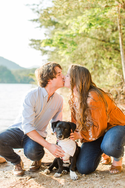 couple kissing with their dog