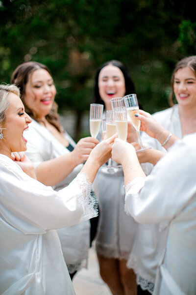 Bridesmaid toasting bride with flutes before she gets in her dress