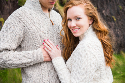 engagement portrait of a girl with red hair, wearing an aran sweater and showing engagement ring