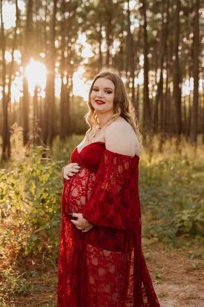 Pregnant Angelica poses in beautiful red dress  in forest outside Houston