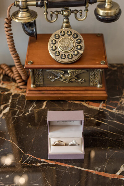 Shelby and Reid's wedding rings are displayed in a box on a luxury marble table as captured by affordable Nashville photographers
