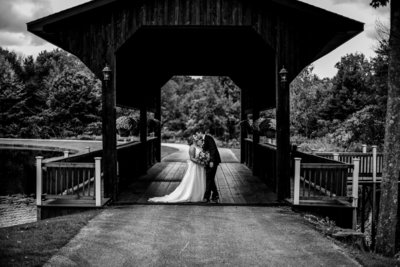 Bride and groom kiss under covered bridge at Majestic Woods