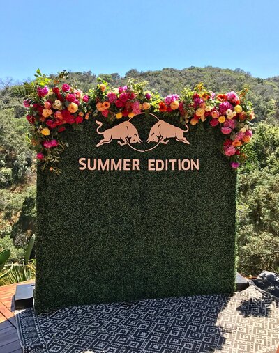 Bright floral installation surrounding a “Summer Edition” event backdrop.