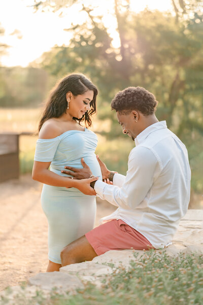 Professional maternity picture of a couple in gorgeous golden light, gazing down at her belly.