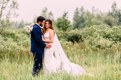 Bride and groom standing in tall grasses at Shanahans Barn in Charlevoix Michigan by Grand Rapids wedding photographer Stephanie Anne