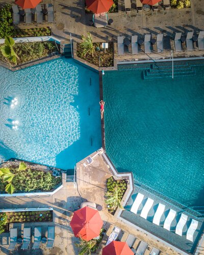Aerial photo of woman in red swimsuit lying between two pools at a Marriott
