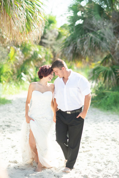 St Simons Island Wedding Day photographed by Megan Holley Photography- Couple is walking on the beach beneath the palm trees.