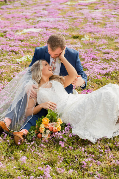 photo of bride and groom laying in flower field after their small wedding in asheville
