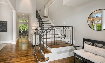 luxury staircase with wide plank solid wood stained floors and black wrought iron railings