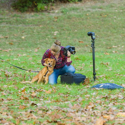 Photographer in grass with dog behind the scenes