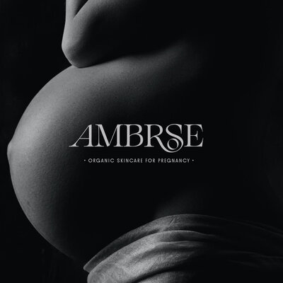 logo design of a brand called Ambrose for an organic skincare brand for pregnancy, logo in white over a black and white photography of a pregnant belly