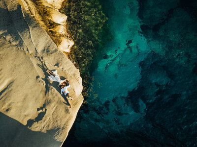 Man and woman lying on rocks drone photo up above of sea