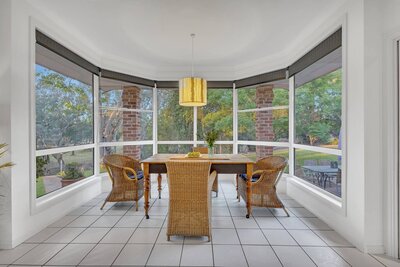 Beautifully styled dining table featuring a wooden tray with candles, decor, and a vase of fresh greenery in a modern home.