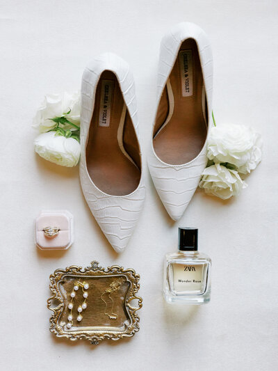 dallas texas wedding featuring bridal details flay lay with ring, perfume, earrings, necklace, shoes, and flowers