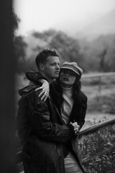 couple sitting on a fence in the rain