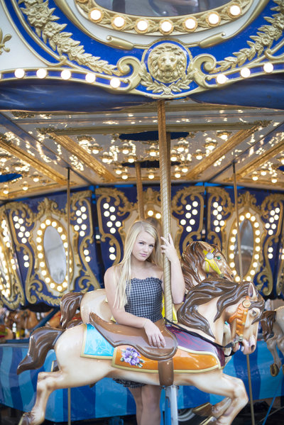 High school senior girl poses on a carousel