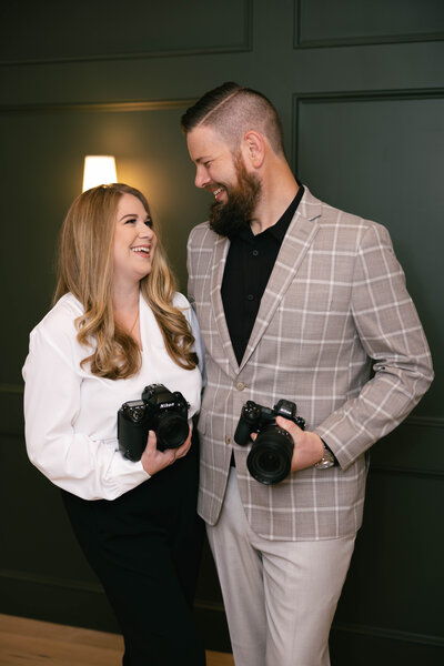 man and woman holding cameras and smiling at each other