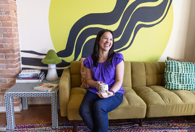 A-Baltimore-graphic-designer-laughs-with-coffee-during-her-artist-loft-brand-photos-in-Baltimore-Maryland