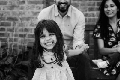 Smiling toddler girl in dress holding her father's hands