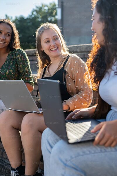 College seniors sitting on their laptops outside in NYC. Showing seniors connecting with their peers thanks to group therapy in Manhattan. College students can find support from fellow students even as they approach the transition of graduation in Manhattan.
