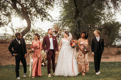 Bride and groom along with bridesmaids and groomsmen walking and smiling at each other in AZ wedding