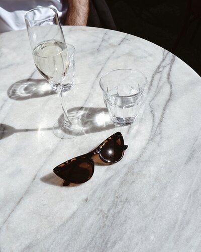 Water glasses on a table next to sunglasses