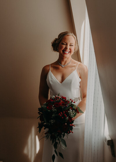 Bride holding bouquet next to window