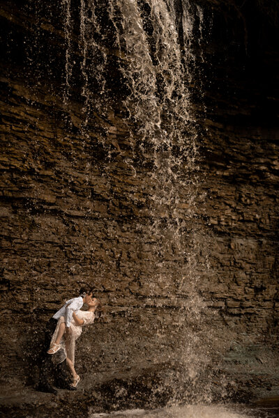Adventurous couple kissing under a waterfall