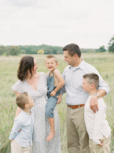 family of 5 during summer family session in a grassy field by madison wi family photographer talia laird photography