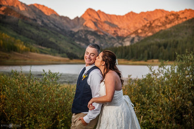 Bride and Groom Kiss with gorgeous orange sunset mountain backdrop at Piney River Ranch