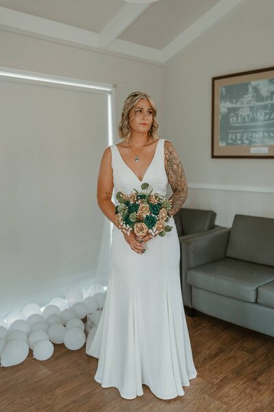 Bride in her wedding dress holding a bouquet during an intimate indoor elopement photoshoot.