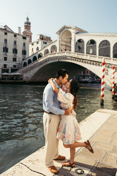 A couple kisses under the iconic landmark Rialto Bridge in Venice Italy