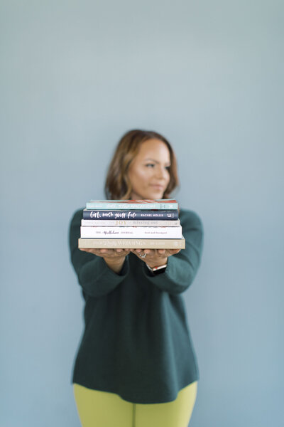Female creative business owner with stack of books