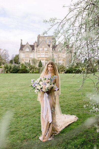 Bride wearing Claire Pettibone wedding gown holding pastel wedding bouquet with veil covering her face in front of De Vere Tortworth Court wedding venue in London, photo by Anastasiya Photography - London Wedding Photographer