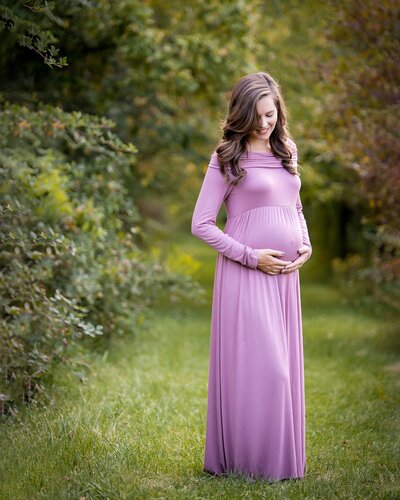 pregnant mother smiling at belly in purple dress