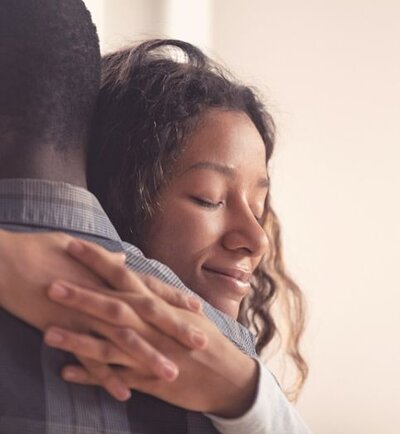 A woman hugs her partner with a warm smile as she interlocks her fingers around him. This could symbolize a new beginning for a couple after healing from infidelity. We offer affair counseling in Florida, and other services. Contact an affair recovery therapist in Florida for support in healing from recovery.