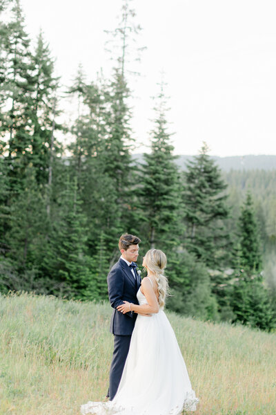 bride and groom facing each other with trees and mountains behind them in Cle Elum Washington