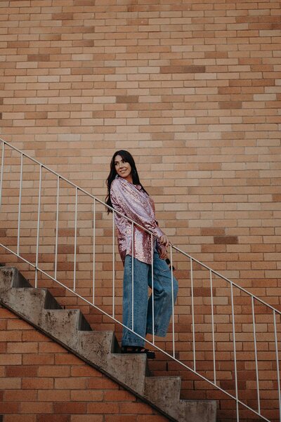 Sharni tolhurst lifestyle photographer near me on an outdoor staircase in front of a brick wall.