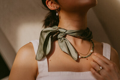 Jewelry brand small business Asian model wearing a bandana around her neck in the sunlight