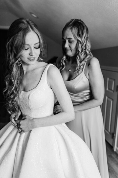 Bride and her mother getting her into her dress on her wedding day