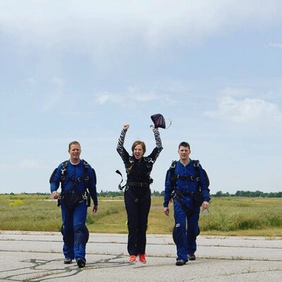 Jackson Hole wedding photographer went skydiving and now walks towards the camera with her arms in the air and smiling