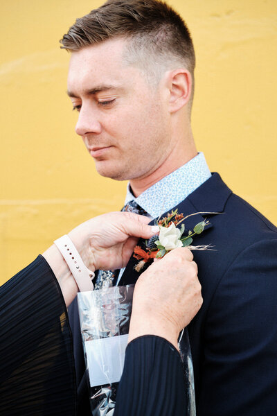 A boutonniere is placed on the groom's jacket