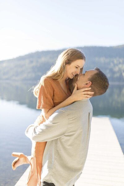 engaged couple hugging in front of lake